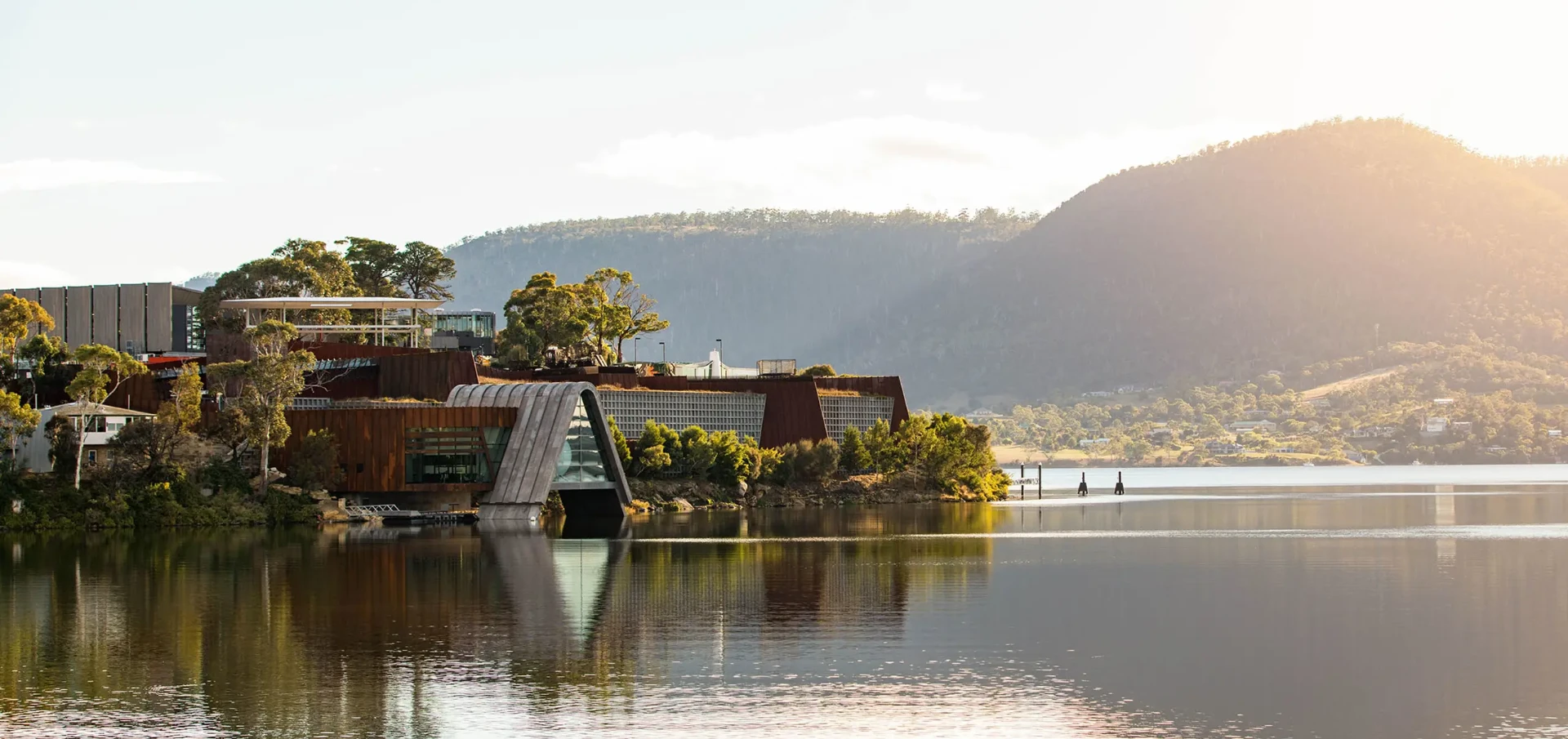 The Museum of Old and New Art on the Derwent River with wooded hills behind