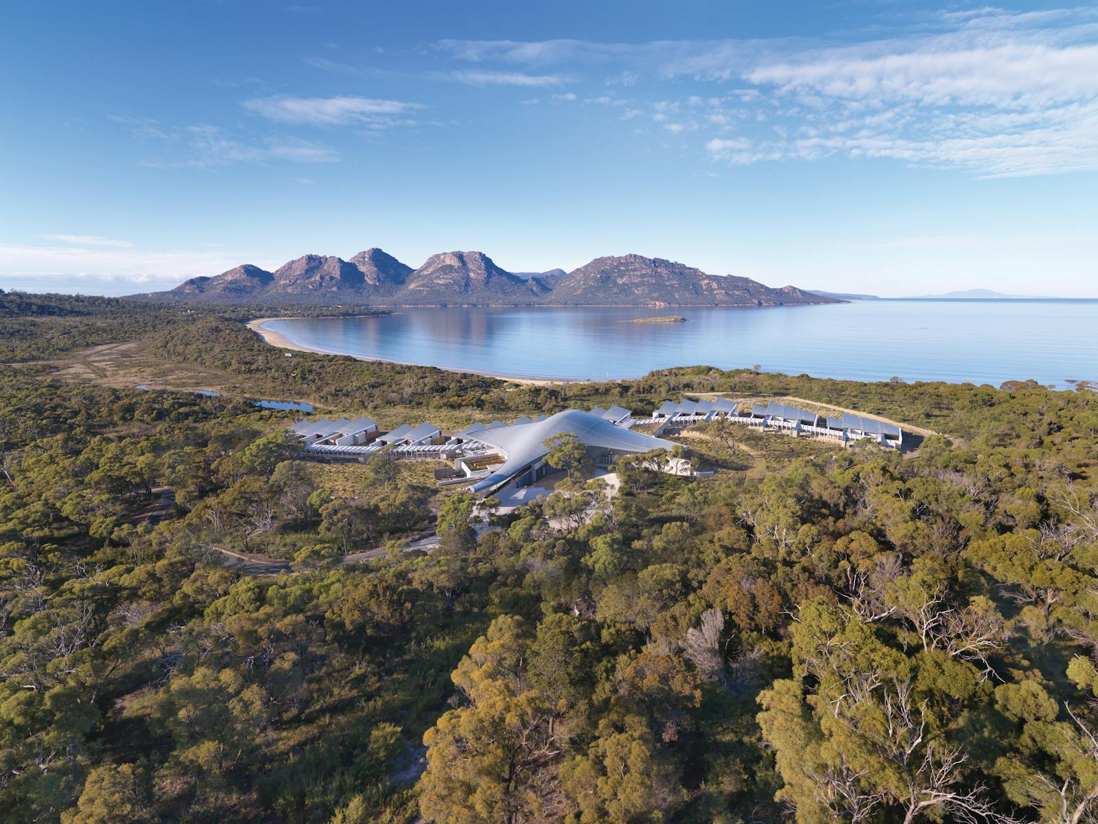 Aerial view of Saffire Freycinet set among coastal bush with Great Oyster Bay and the Hazards range beyond