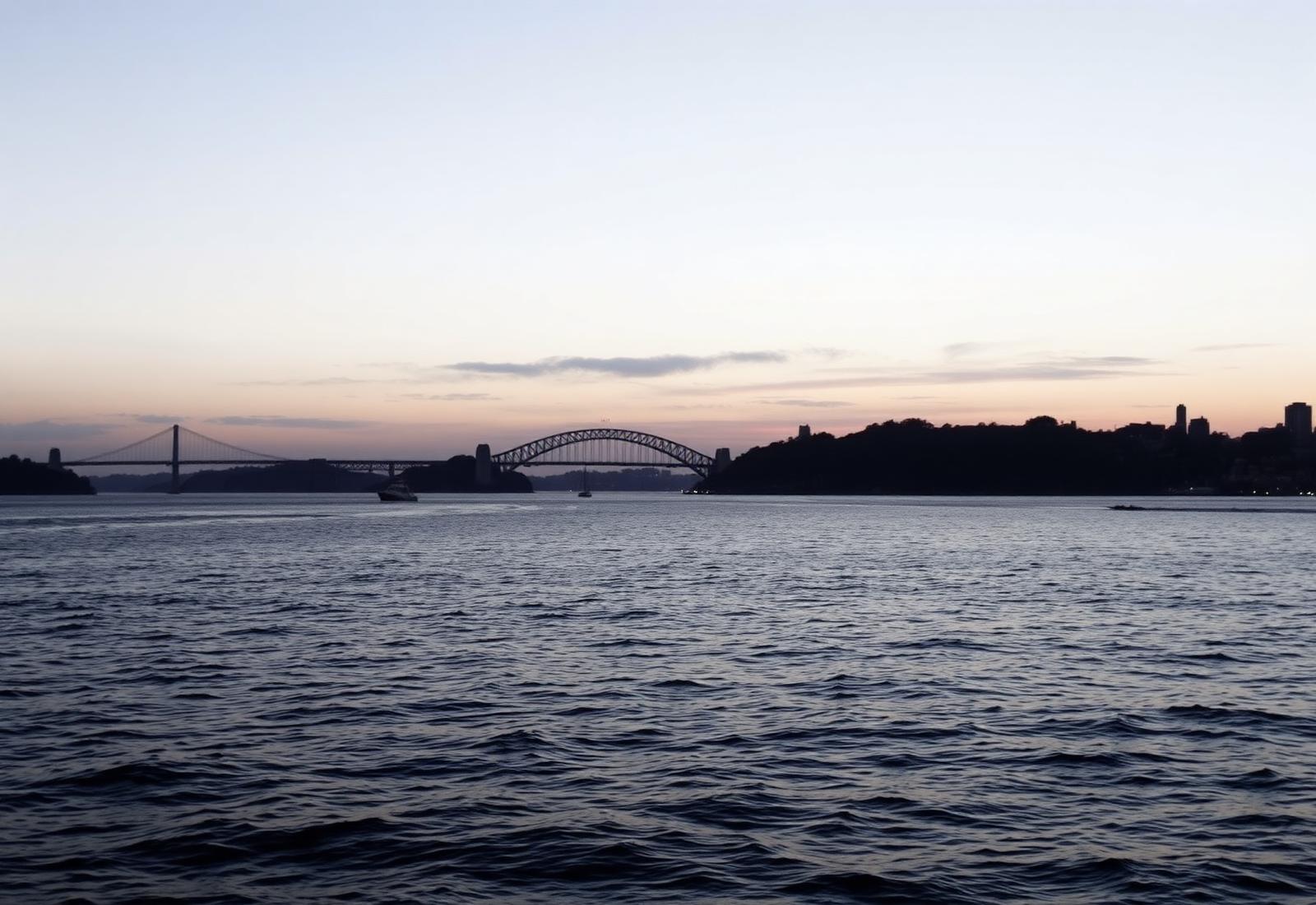 Sydney Harbour at first light seen from the water, a deep navy sea beneath a pale sky.
