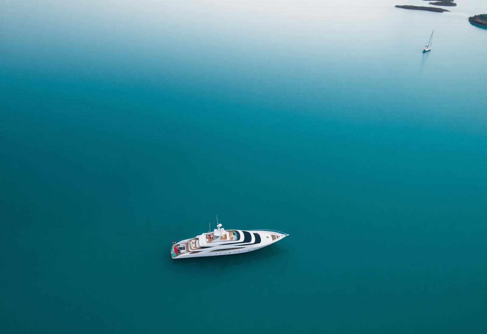 A modern superyacht anchored in the still turquoise water of a Whitsunday bay.